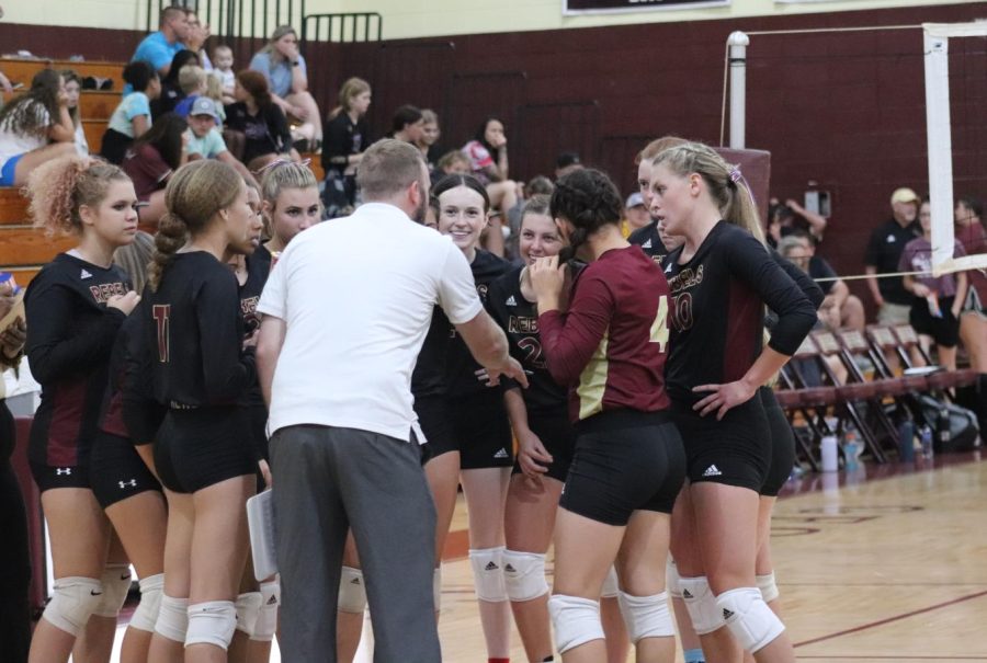 The volleyball team gathers in a group huddle during the game.