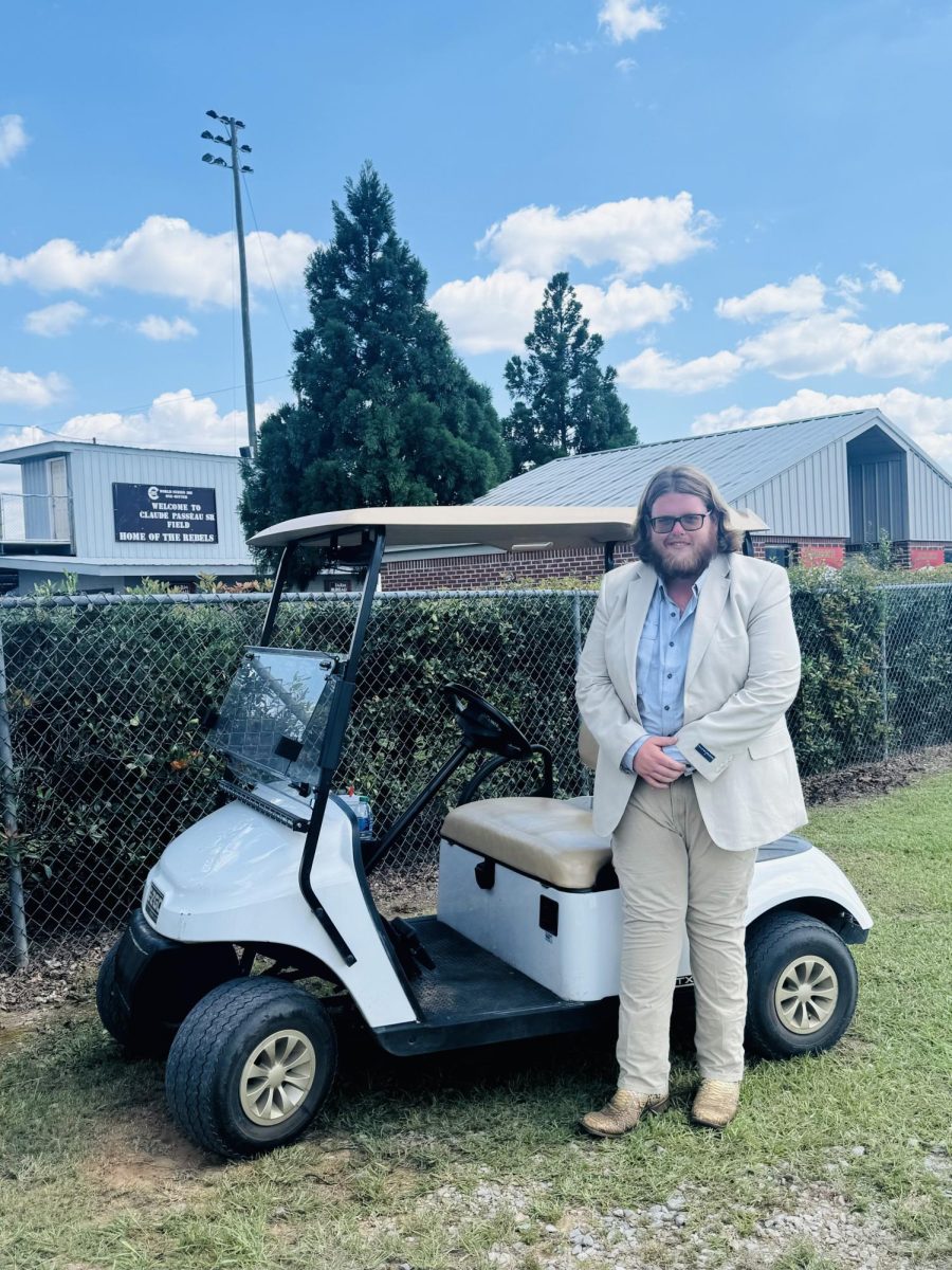 Forrest Ford stands with golf cart he was gifted by the GCHS Rebel Baseball Team